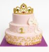 Two-tier pink fondant Royal Crown Theme Cake with golden tiara topper and bow decoration – princess birthday cake