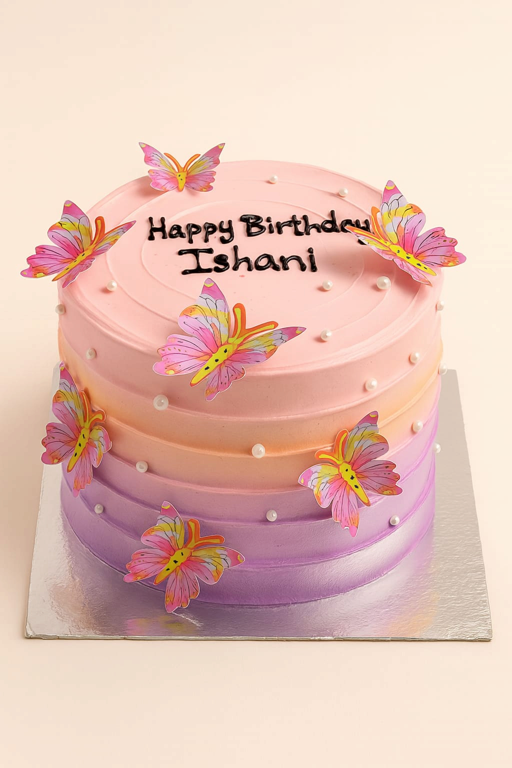 A round pink and purple ombre birthday cake decorated with edible sugar butterflies and pearls, with Happy Birthday written on top